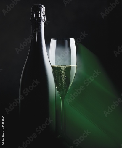 Photo: Bottle and glass of sparkling wine in green light Bottle and glass of sparkling wine in green light