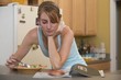 Young woman eating fruit-flavoured cereal loops, reading newspaper