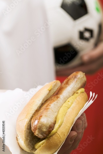 Photo: Footballer holding hot dog (sausage & mustard in bread roll) Footballer holding hot dog (sausage & mustard in bread roll)