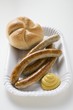 Four sausages with mustard and bread roll