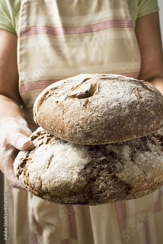 Photo: Woman holding two loaves of bread in her hands Woman holding two loaves of bread in her hands