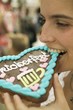 Woman biting into Lebkuchen heart at Oktoberfest
