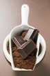 Pieces of chocolate and cocoa powder in scoop and bowl
