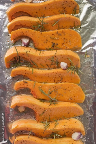 Foto: Pumpkin slices with rosemary and garlic on aluminium foil Pumpkin slices with rosemary and garlic on aluminium foil