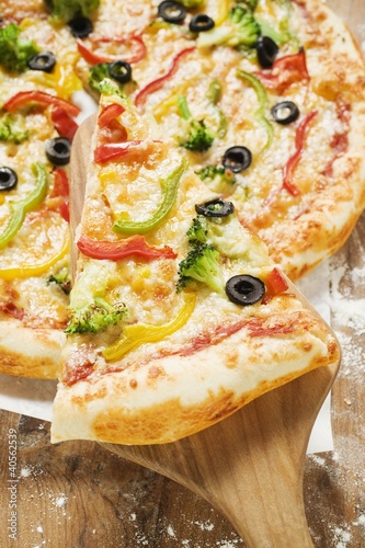Photo: American-style vegetable pizza with piece on server American-style vegetable pizza with piece on server