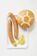 Frankfurters, bread roll and mustard on paper plate