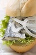 Bread roll filled with herring and onions on paper napkin