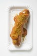Sausage with ketchup and curry powder on paper plate