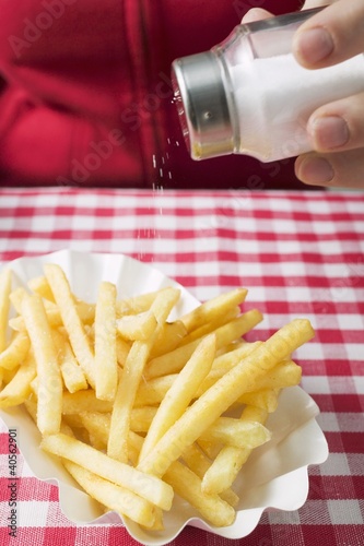 Photo: Hand sprinkling salt on chips Hand sprinkling salt on chips