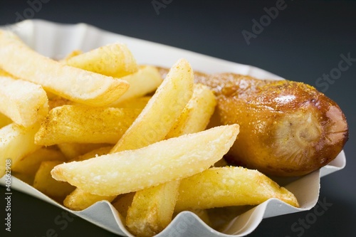 Photo: Currywurst (sausage with ketchup & curry powder) & chips in paper dish Currywurst (sausage with ketchup & curry powder) & chips in paper dish