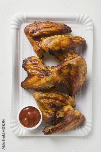 Photo: Grilled chicken wings with ketchup on paper plate Grilled chicken wings with ketchup on paper plate