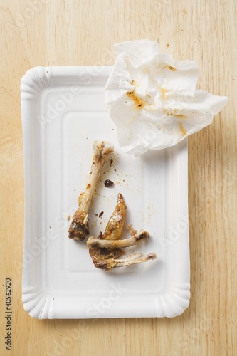 Photo: Chicken bones and paper napkin on paper plate Chicken bones and paper napkin on paper plate
