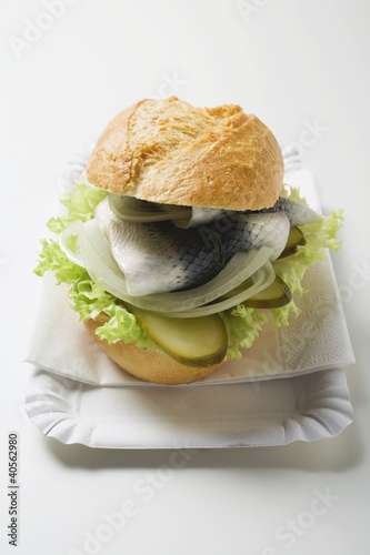 Photo: Herring, onions & gherkins in bread roll on paper plate Herring, onions & gherkins in bread roll on paper plate