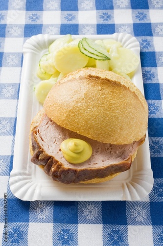 Photo: Leberkäse in roll with mustard & potato salad on paper plate Leberkäse in roll with mustard & potato salad on paper plate