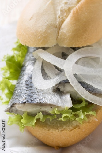 Photo: Bread roll filled with herring and onions on paper napkin Bread roll filled with herring and onions on paper napkin