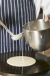 Foto: Pouring pancake mixture onto hotplate Pouring pancake mixture onto hotplate