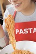 Foto: Young woman in apron eating spaghetti with tomato sauce Young woman in apron eating spaghetti with tomato sauce