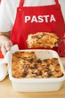 Foto: Woman taking portion of lasagne out of baking dish Woman taking portion of lasagne out of baking dish
