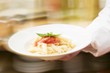 Chef serving penne with tomato sauce
