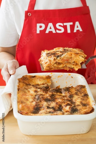 Photo: Woman taking portion of lasagne out of baking dish Woman taking portion of lasagne out of baking dish