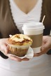 Woman holding muffin and cup of coffee