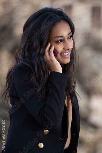 Photo: Portrait of a happy young black teenage girl using a mobile pho Portrait of a happy young black teenage girl using a mobile pho