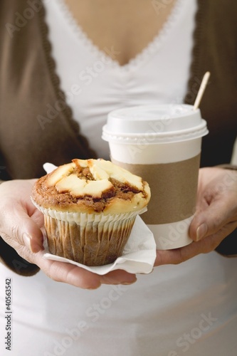 Photo: Woman holding muffin and cup of coffee Woman holding muffin and cup of coffee