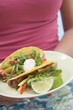 Foto: Woman holding plate with two tacos Woman holding plate with two tacos