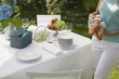 Foto: Woman carrying baguettes to table laid out of doors Woman carrying baguettes to table laid out of doors
