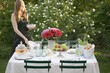 Foto: Woman putting plates on table laid out of doors Woman putting plates on table laid out of doors