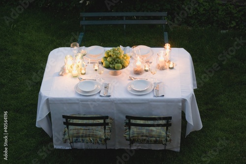 Photo: Bowl of fruit and windlights on table laid in garden Bowl of fruit and windlights on table laid in garden