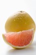 Wedge of pink grapefruit in front of whole grapefruit