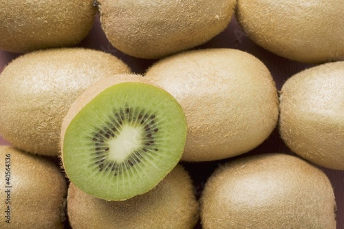 Photo: Half a kiwi fruit on several whole kiwi fruits Half a kiwi fruit on several whole kiwi fruits