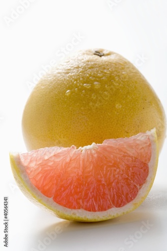 Photo: Wedge of pink grapefruit in front of whole grapefruit Wedge of pink grapefruit in front of whole grapefruit