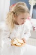 Small girl with angel's wings holding plate of biscuits