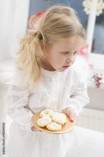Foto: Small girl with angel's wings holding plate of biscuits Small girl with angel's wings holding plate of biscuits