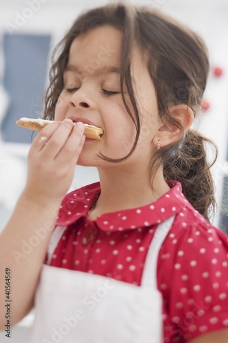 Photo: Small girl eating Christmas biscuit she has made herself Small girl eating Christmas biscuit she has made herself
