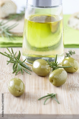Foto : Olive oil, green olives and rosemary on chopping board Olive oil, green olives and rosemary on chopping board