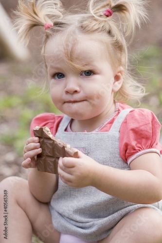 Photo: Little girl holding part of a bar of nut chocolate Little girl holding part of a bar of nut chocolate