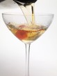 Pouring Manhattan out of cocktail shaker into glass