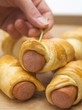 Photo: Hand pushing cocktail stick into sausage roll Hand pushing cocktail stick into sausage roll