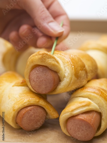 Photo: Hand pushing cocktail stick into sausage roll Hand pushing cocktail stick into sausage roll