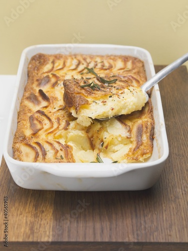 Photo: Potato gratin in baking dish with piece on server Potato gratin in baking dish with piece on server