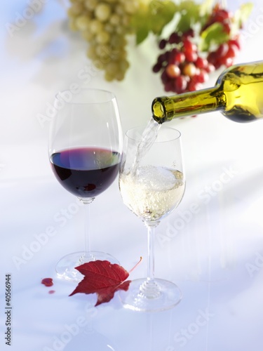Foto: Pouring white wine into glass, glass of red wine, grapes, autumn leaf Pouring white wine into glass, glass of red wine, grapes, autumn leaf
