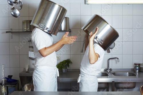 Foto: Two chefs having discussion with large pans on their heads Two chefs having discussion with large pans on their heads