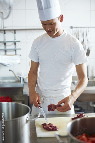 Photo: Young chef cutting up beef Young chef cutting up beef