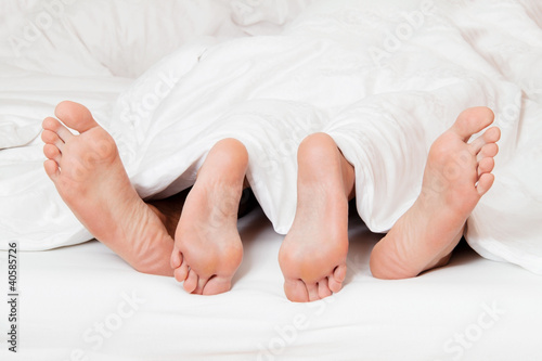 Foto: Füße eines Paares im Bett. Füße eines Paares im Bett.