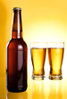 Two glasses and Bottle of fresh light beer on yellow background