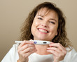 Happy middle-aged woman holding a positive pregnancy test
