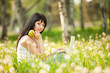 Cute woman with white laptop in the park with dandelions
